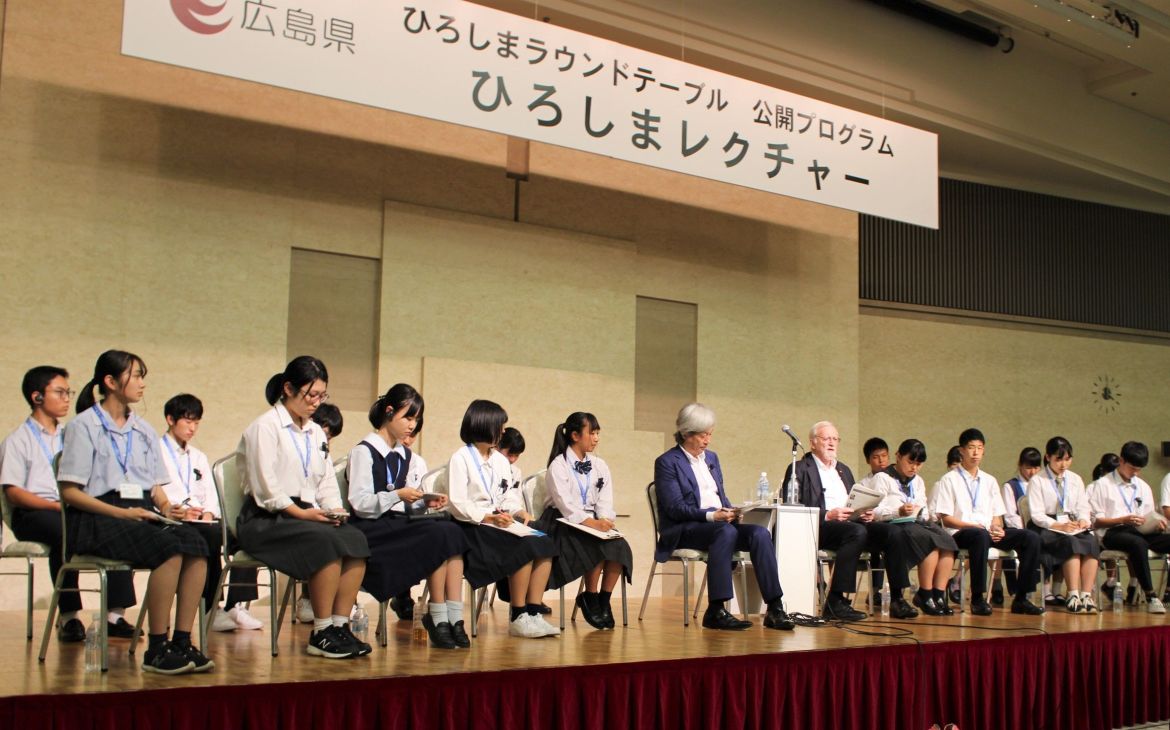 Youth Ambassadors and lecturers are seated on stage