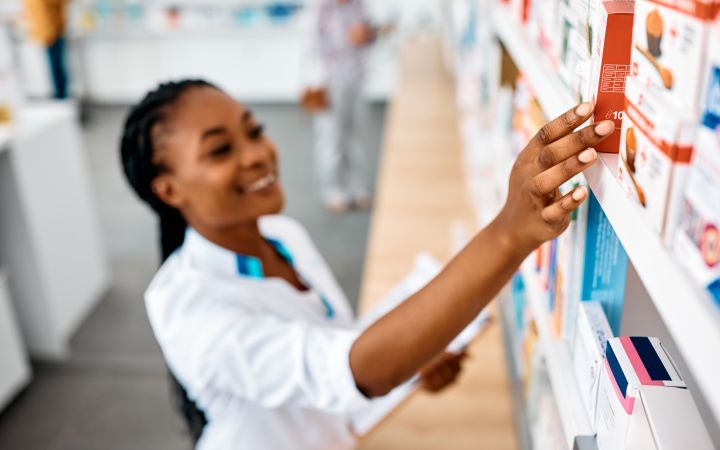 African pharmacist reaching to a medicine stacked in a shelf