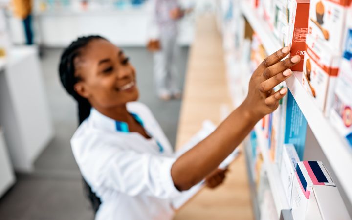 African pharmacist reaching to a medicine stacked in a shelf