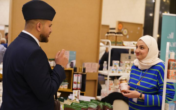 Shumoos Ghanim Jaber manning her stall, showing a product to a customer
