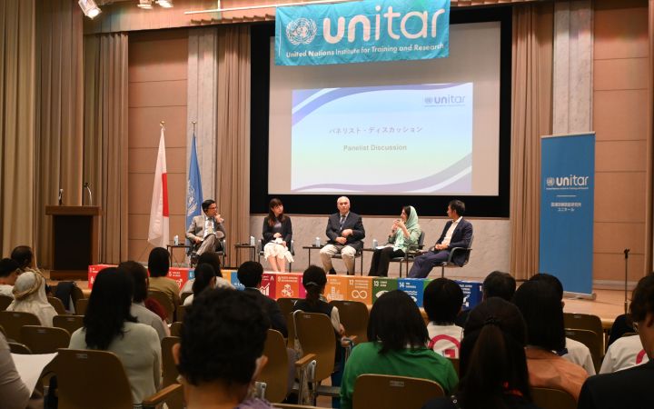 A photo showing audiences looking on stage where a group of people comprised of three men and women are discussing.