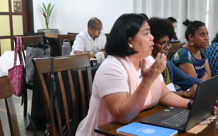 A woman discussing something to an audience (not shown) beside her (right side of the photo) are other women participants from different countries.