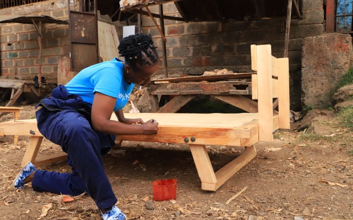 Mwikali painting the bed frame she created