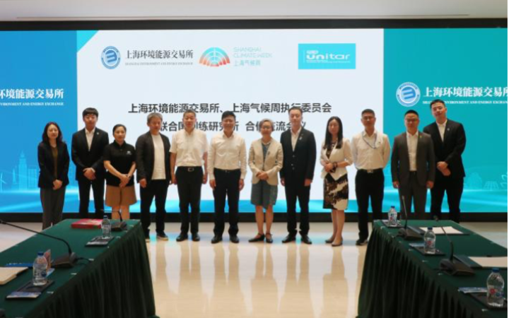 Twelve Asian men and women in business attire pose in a row in front of a brightly lit backdrop with the meeting title in Chinese and various logos of the participating organizations.