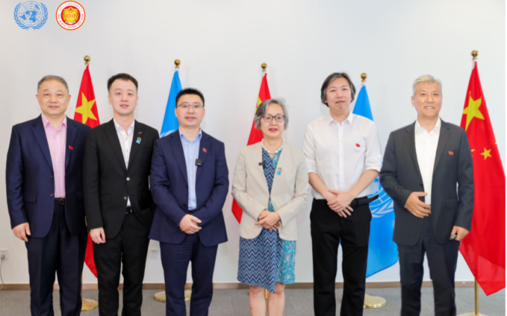 Five Asian men in suits and an Asian woman in a jacket and blue dress stand in a row in front of alternating standing flags of the United Nations and China.]