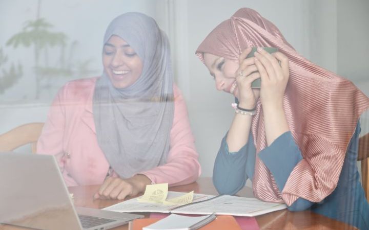 Two women are smiling while looking a laptop